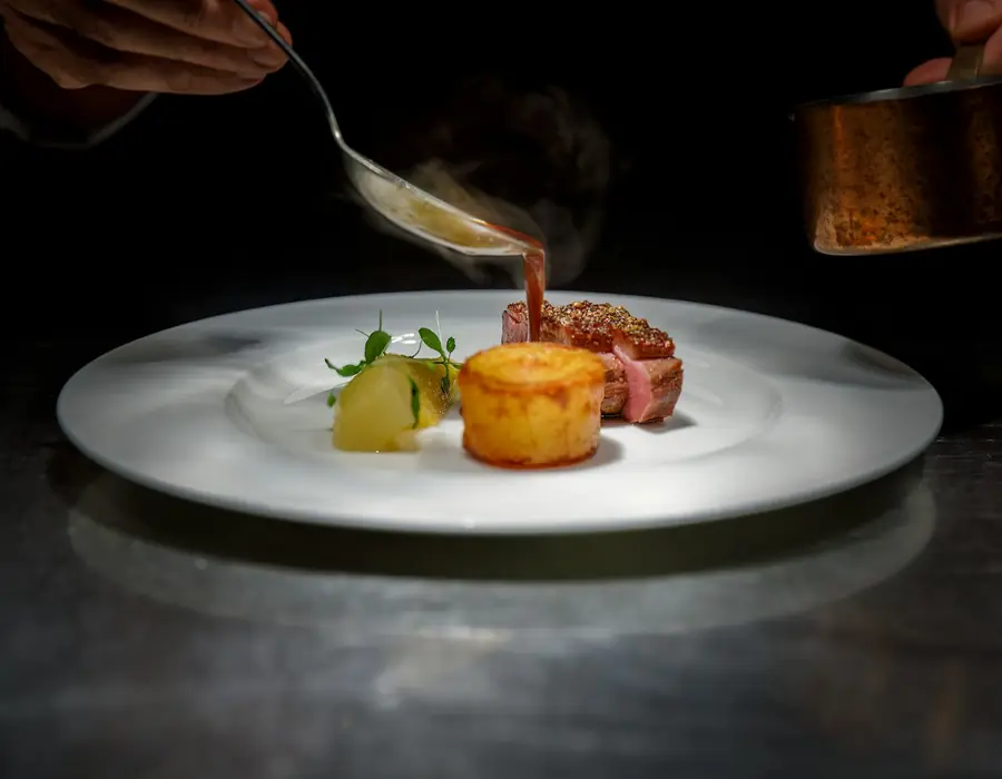 Chef finishing a plated dish